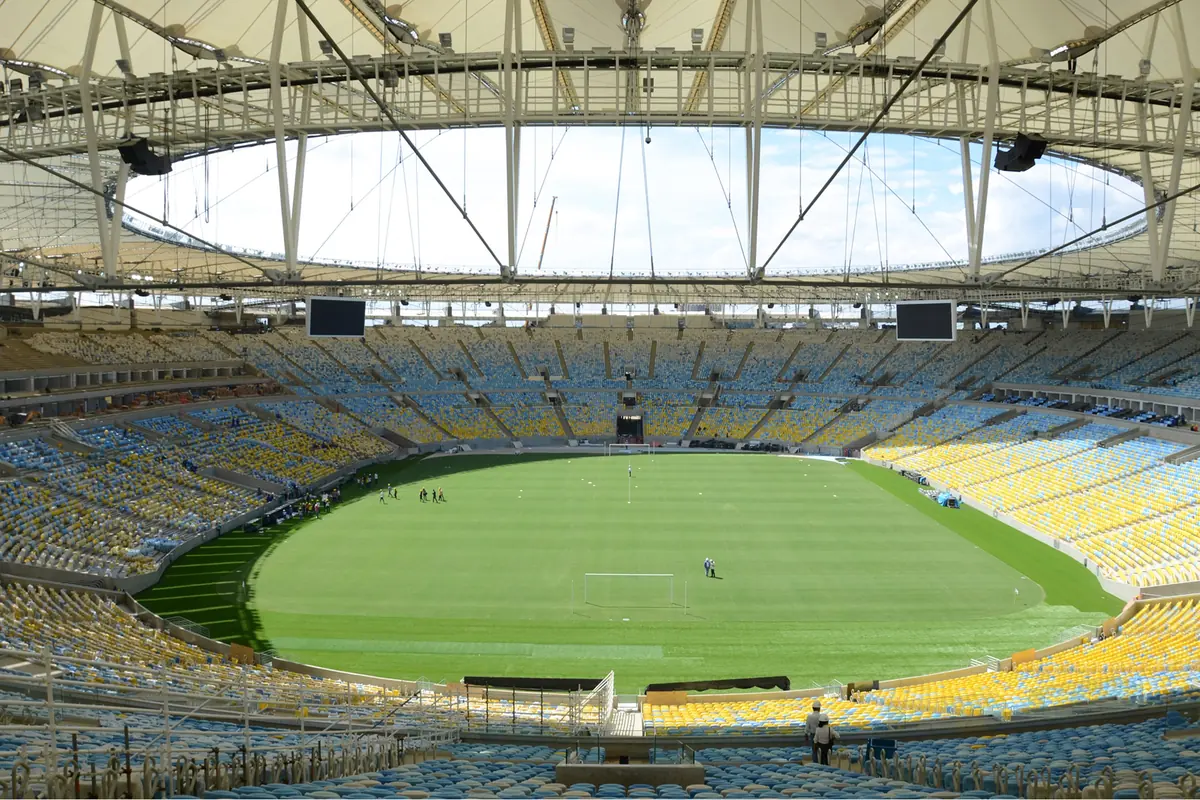The inside of the Maracanã stadium, with tiers of yellow, blue and white seats around a green pitch beneath a ring-shaped roof