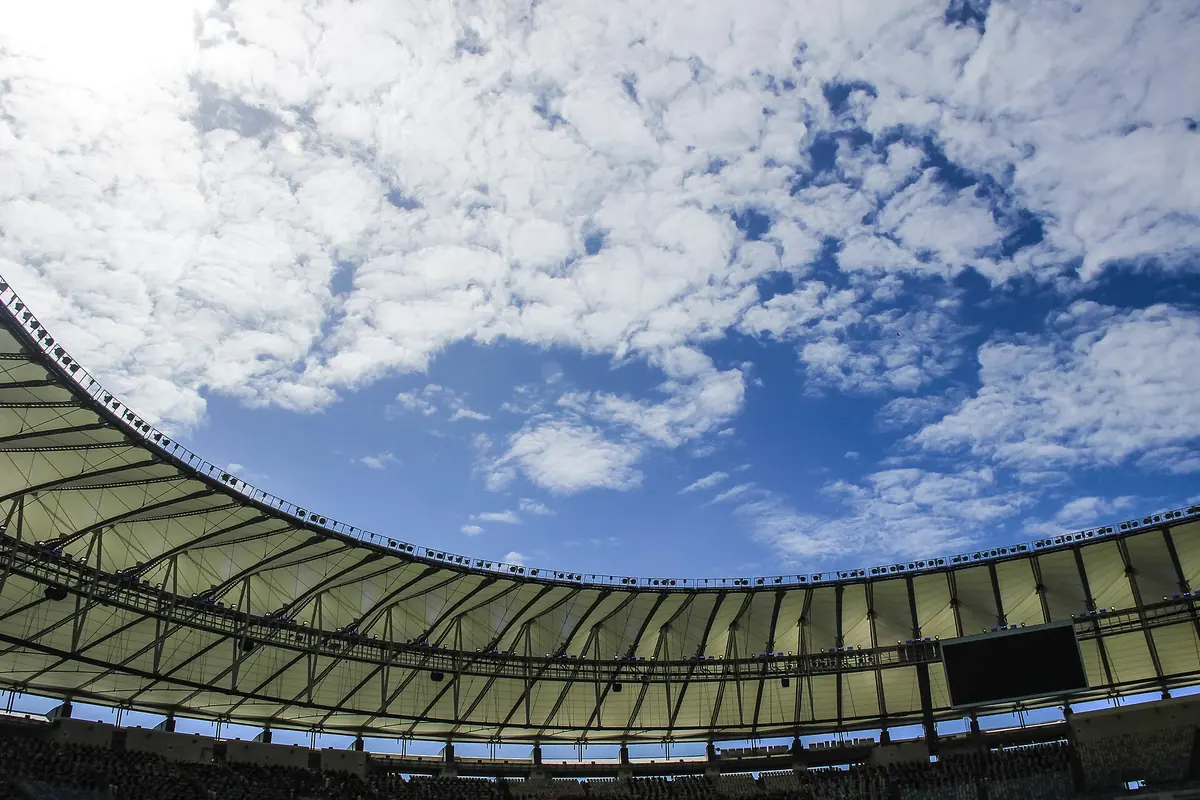 The ring-shaped roof of the Maracanã seen from inside the stands, with a pale membrane and steel cables around an opening to the sky