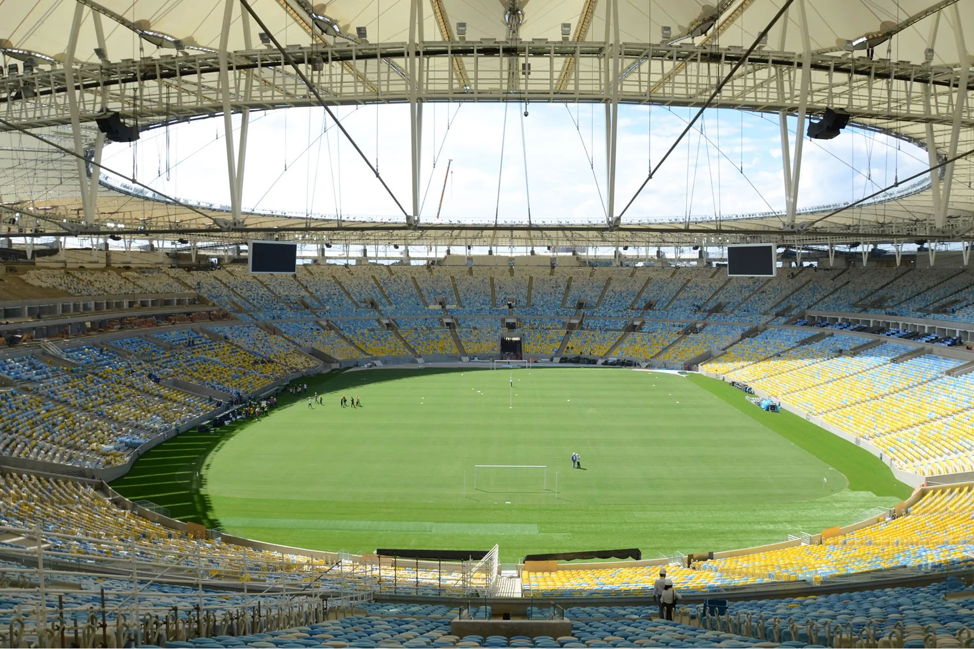 The inside of the Maracanã stadium in Rio de Janeiro, with tiers of yellow, blue and white seats around a green pitch beneath a ring-shaped roof