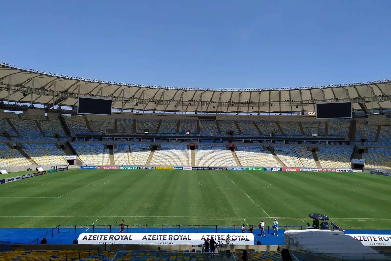 The Maracanã seen from a seat in the upper tier, with a green pitch below banks of yellow, blue and white seats and a pale roof ring above